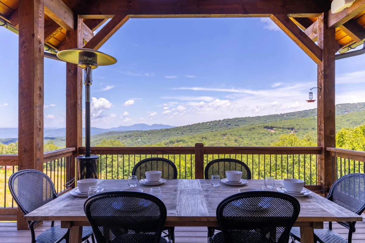 An al fresco dining area with a table and chairs set against a stunning mountain view. The space is equipped for outdoor meals and gatherings, offering both sunrise breakfasts and sunset dinners in a breathtaking natural environment.