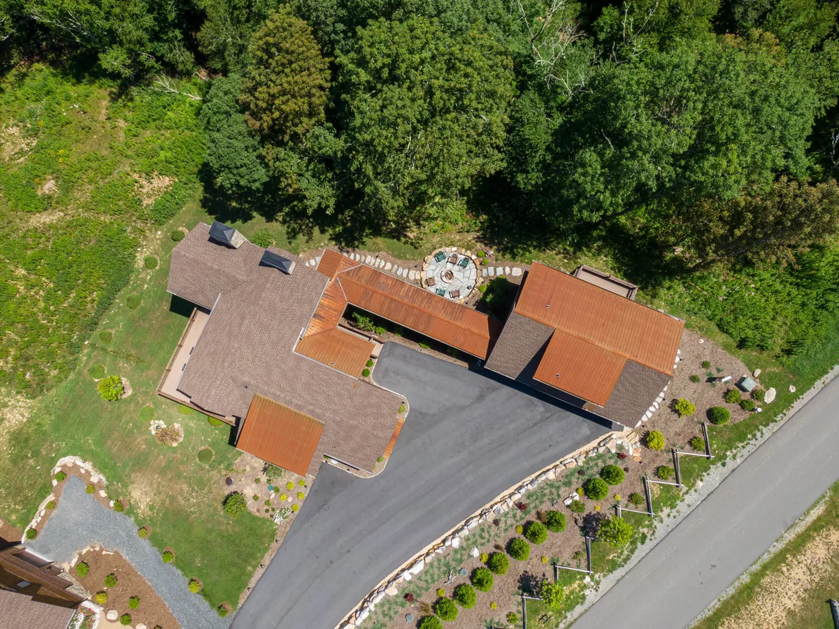 A welcoming house exterior with a landscaped garden and a dedicated fire pit area. The inviting setup signals a space ideal for evening s'mores or relaxing after a day of adventure, supporting family bonding moments around the fire.