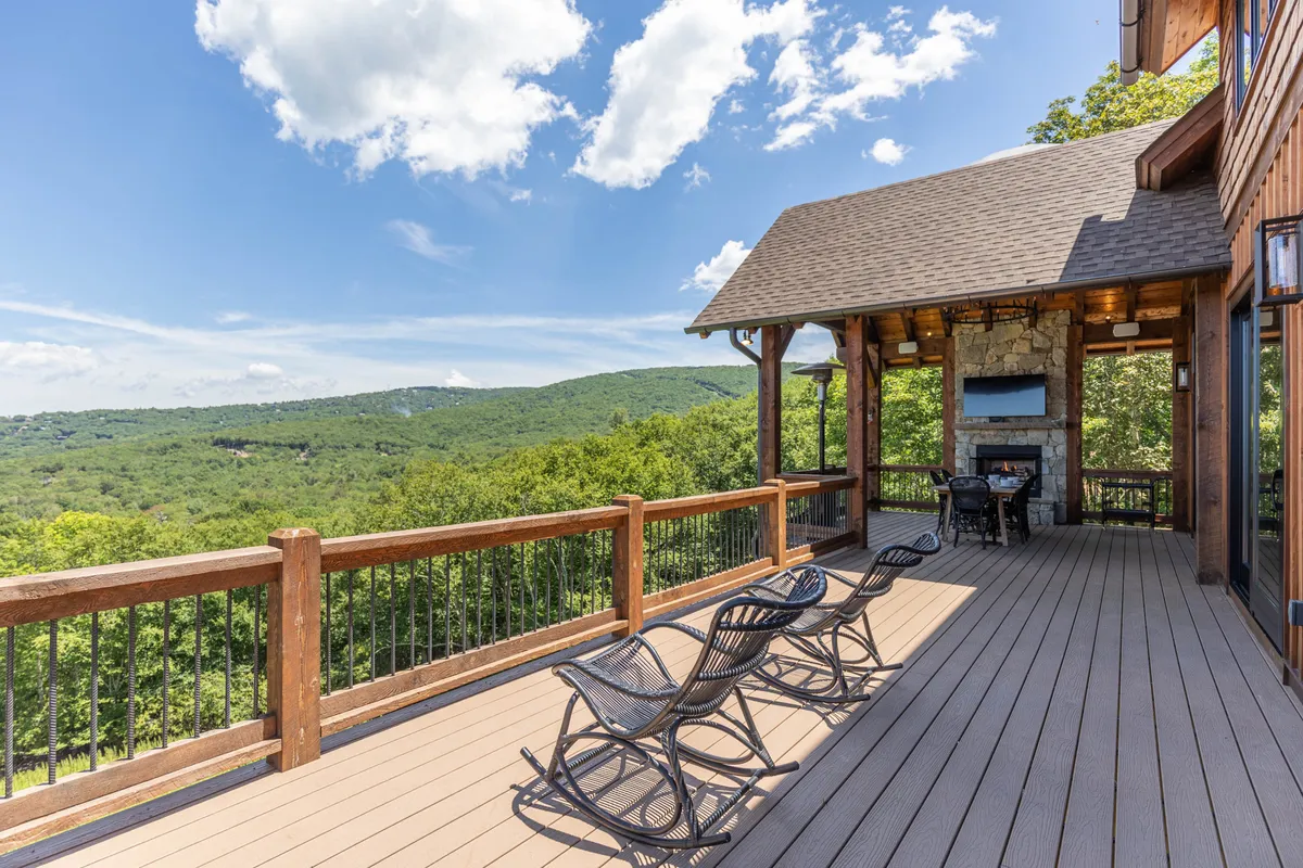A scenic deck area with rocking chairs, an outdoor fireplace, and a breathtaking mountain backdrop. This space invites relaxation, socializing, and soaking in the natural surroundings—perfect for both energetic activities and peaceful moments.