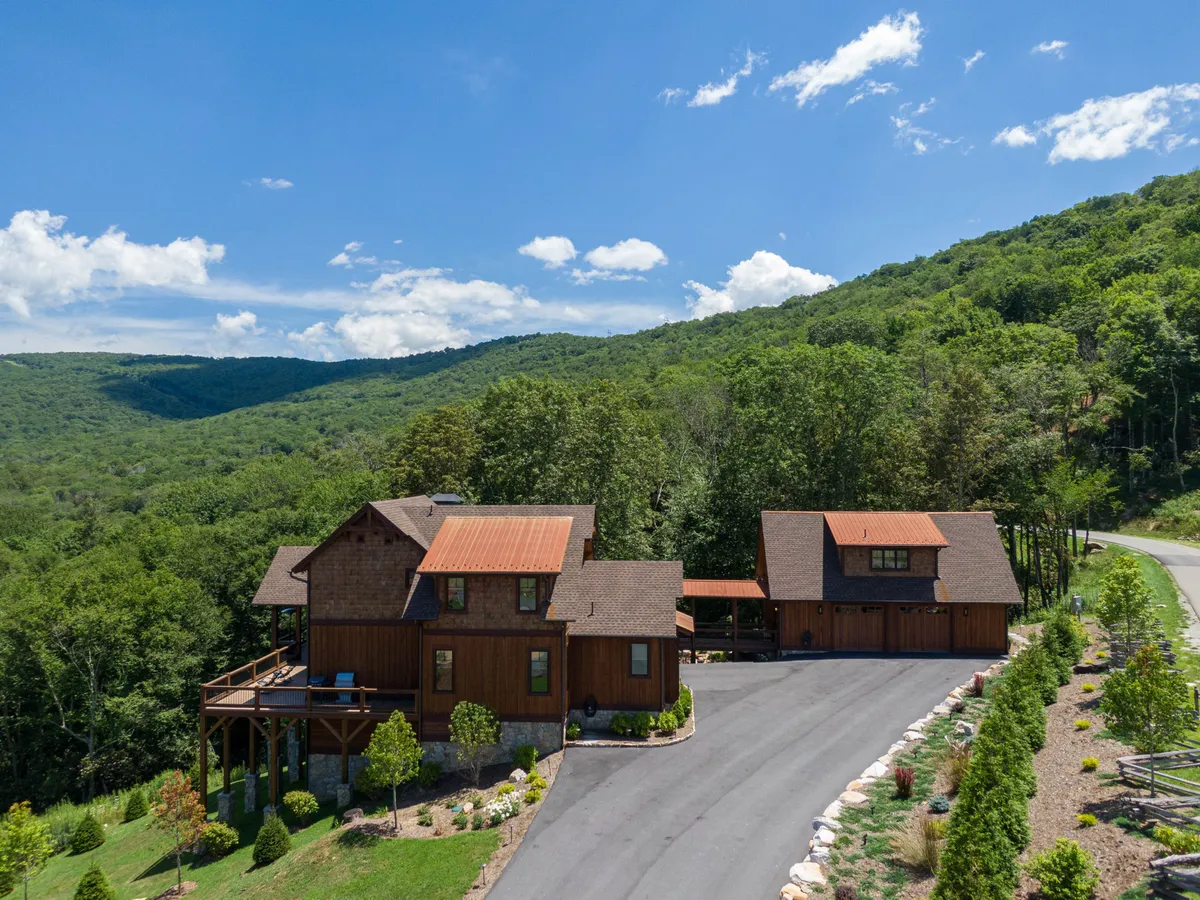A bright, inviting exterior shot featuring Breezeway Lodge’s main house and separate garage with carriage house suite above, surrounded by a landscaped garden and lush greenery. The setup visually conveys the property’s unique layout and ample space for multiple generations to gather, relax, and explore outdoors.