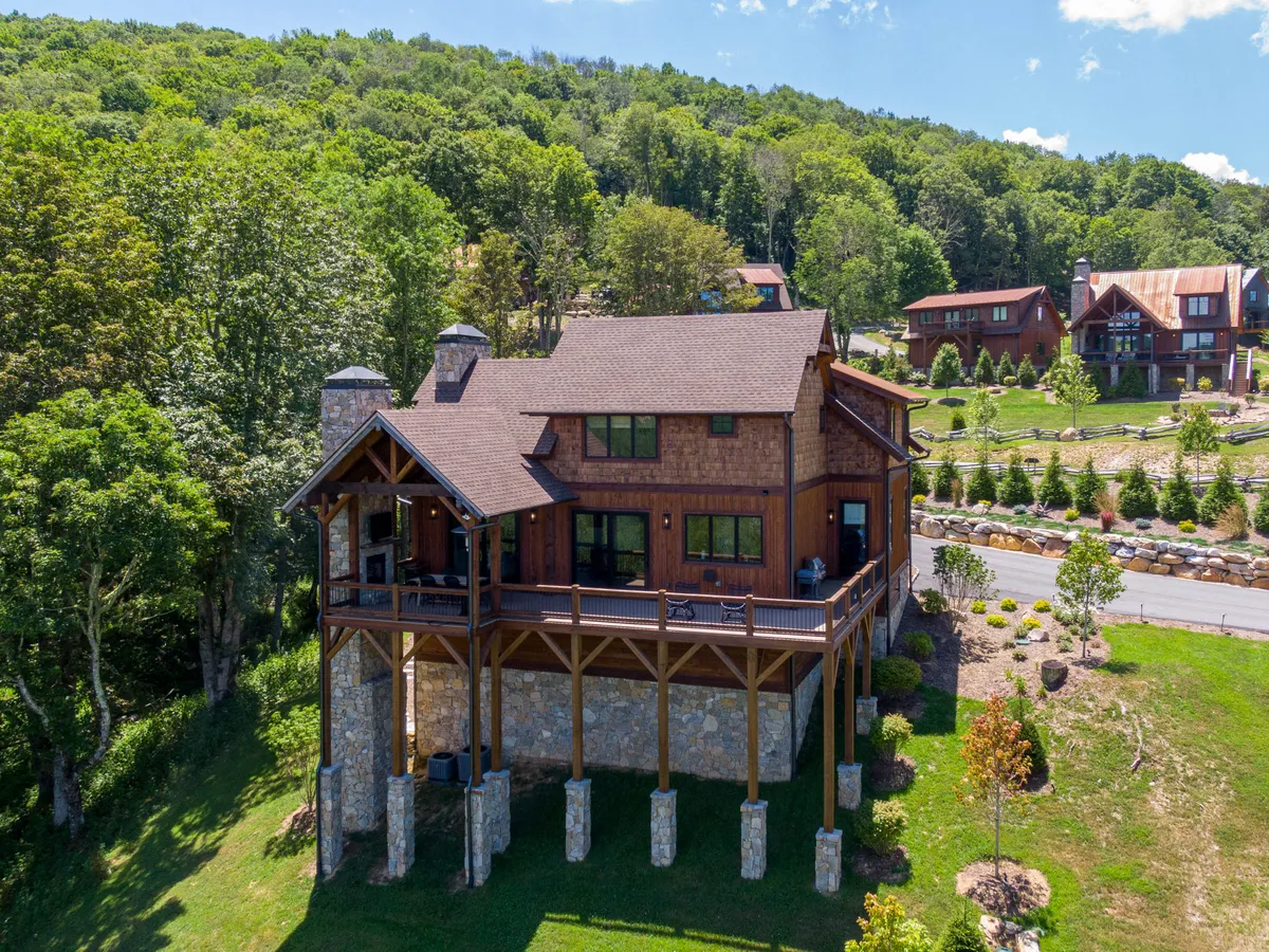 A welcoming exterior image of the lodge showcasing a wooden structure with stone pillars, surrounded by lush greenery. The ambiance is serene, hinting at both the comfort of the lodge and its proximity to outdoor recreation.